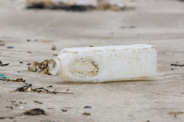 Plastic drink bottle washed up on a sandy beach an example of the many pieces of garbage in the sea around the world