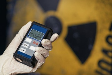 Radiation supervisor in glove with geiger counter checks the level of radiation