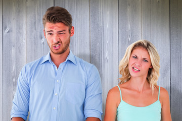 Young couple making silly faces against wooden planks