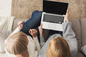 Adult woman and daughter using laptop top view