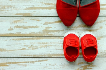 Two red shoes or sneakers of mother or father and child on wooden background,use for father's day or mother's day or family's day with sport concept