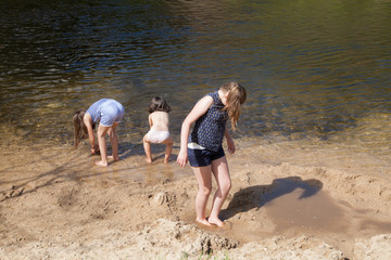 Trois filles jouant dans le sable au bord de la rivière