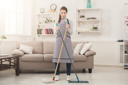 Smiling woman cleaning house with mops