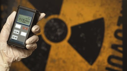 Radiation supervisor in glove with geiger counter checks the level of radiation
