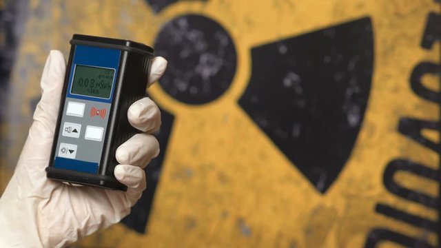 Radiation supervisor in glove with geiger counter checks the level of radiation