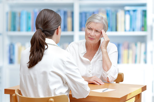 Female Doctor With A Senior Patient Suffering Of Chronic Headache, Migraine Or Brain Fog Caused By Long Covid.