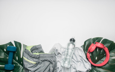 concept of sports lifestyle, sportswear and accessories lined up on a white background, with a bottle of water and tropical leaves, space for text