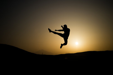 Athlete jump high with energy. Sportsman silhouette on sunset sky. Man training on natural...