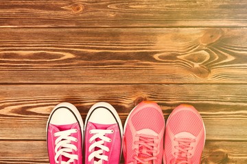 Pink sneakers on wooden texture