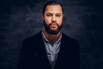 Obraz premium Studio portrait of handsome Afro-American male in an elegant black jacket and hat.