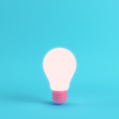 Pink glowing light bulb on bright blue background in pastel colors
