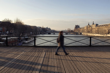 Fototapeta na wymiar Blurry motion image of a woman walking on Pont des Arts bridge on Seine river in Paris.
