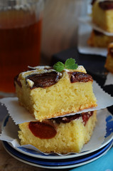 Coconut cake with plums. Two pieces of cake on white plate.