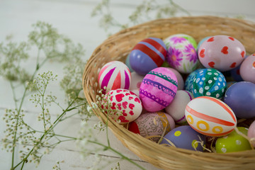 Basket with painted Easter eggs on wooden background