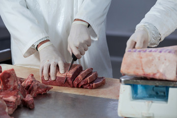 Butchers cutting meat and checking the weight of meat at meat factory