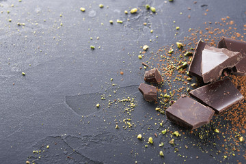 Dark chocolate pieces and cocoa powder over black background