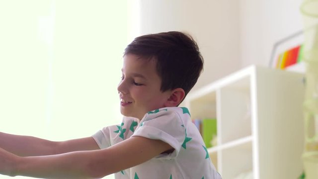 childhood, imagination and dream concept - happy little boy playing with airplane toy at home