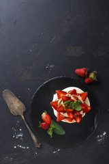 Fototapeta na wymiar Delicious Anna Pavlova meringue cake with strawberry on black background