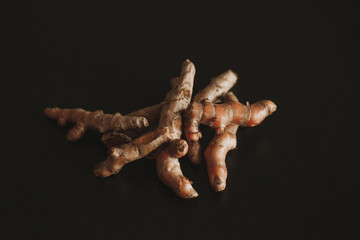 Close up of turmeric roots on a black table.