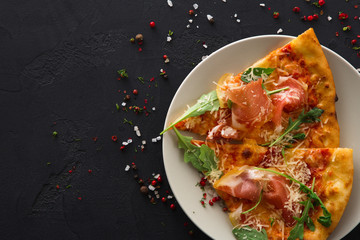 Sliced pizza with prosciutto and rocket salad