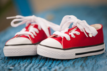 Red baby sneakers on wooden blue background