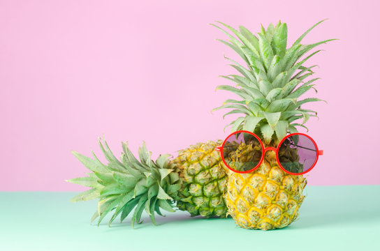 Pineapples with red sunglasses on yellow background - Summer background