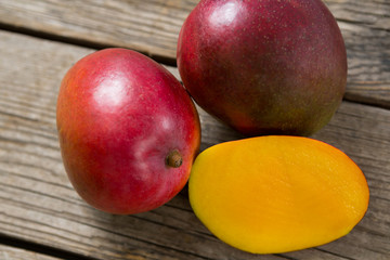 Halved mangoes on wooden table