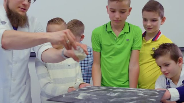 Children looks at dancing sand on chladni plate in laboratory