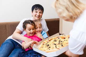 Portrait of happy family eating pizza while sitting on sofa at home