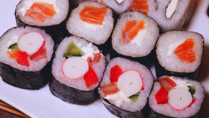 Fresh sushi, Philadelphia cheese, crab sticks, salmon, rice, ginger, soy, orange background, macro.