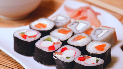 Fresh sushi, Philadelphia cheese, crab sticks, salmon, rice, ginger, soy, orange background, macro.