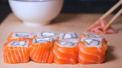 Fresh sushi, Philadelphia cheese, crab sticks, salmon, rice, ginger, soy, orange background, macro.
