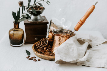 Hot coffee in Turkish Cooper and coffee beens on linen table