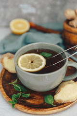 Hot tea with lemon and fresh ginger on rustic scene.