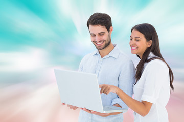 Attractive young couple holding their laptop against digitally generated pink and blue girly design