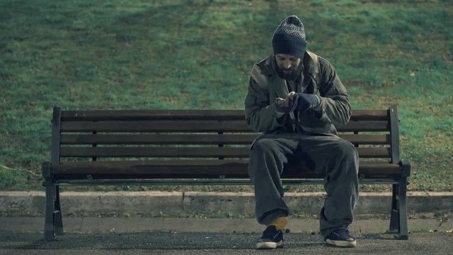 Homeless sit on bench at night counting his money