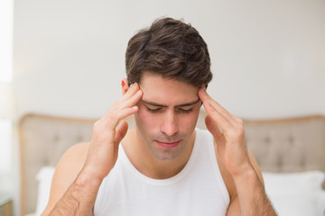 Close up of a man suffering from headache in bed