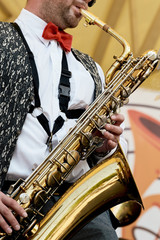 A closeup is masculine, playing on a gold saxophone.