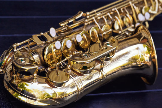 Closeup of a beautiful saxophone lying on a bench.