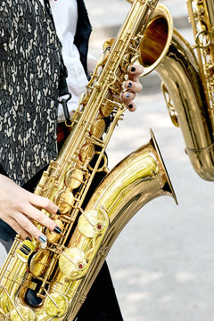 Closeup of a girl with two beautiful gold saxophone in the park.
