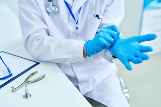 Mid section portrait of unrecognizable doctor putting on blue rubber gloves, copy space