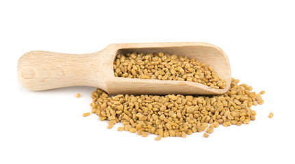 Fenugreek seeds in wooden spoon, isolated on white background