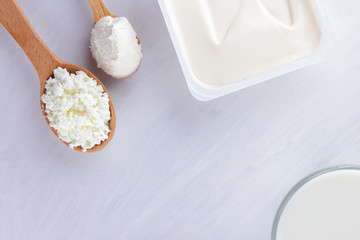 Fototapeta na wymiar Dairy products on a white board. Cottage cheese, cream and soft cheese on a white background. Milk in a glass, soft cheese for sandwiches. Wooden cutlery. Copy space