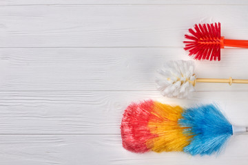 Colorful brushes for house cleaning. House cleaning supplies on white wooden background, copy space. Cleaning service concept.