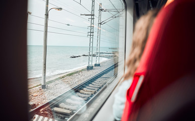 Closeup of a train seat. Beautiful view from the train window to the sea. Travel by train by sea. The girl sits at the window and looks at the blue sea. Railways from the window