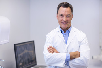 Portrait of happy dentist standing with arms crossed