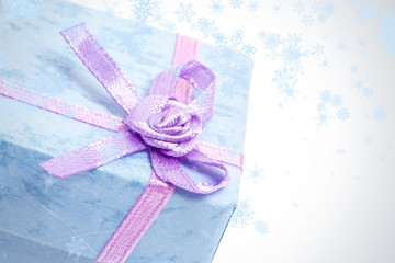 Snow falling against close up of blue gift box with purple ribbon
