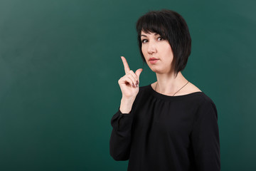 teacher having idea and posing by chalk Board, learning concept, green background, Studio shot
