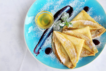 baked pancakes with mint honey powdered sugar and sauce on blue plate