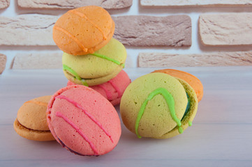 Heap of colored biscuit cakes with jam on beige brick background